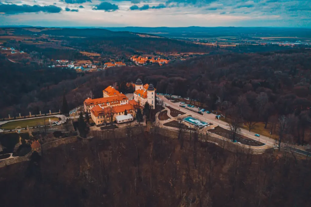 Widok z lotu ptaka na zabudowania przedzamcza i otaczający je park w zimowym krajobrazie, historyczny kompleks zamkowo-parkowy Książ i dawna posiadłość arystokratycznego rodu Hochbergów